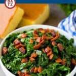 Mustard greens in a bowl with bacon bits on top and corn bread next to the bowl.