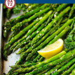 A sheet pan with roasted asparagus seasoned with garlic and herbs.