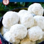 A tin with snowball cookies piled high and coated with powdered sugar.