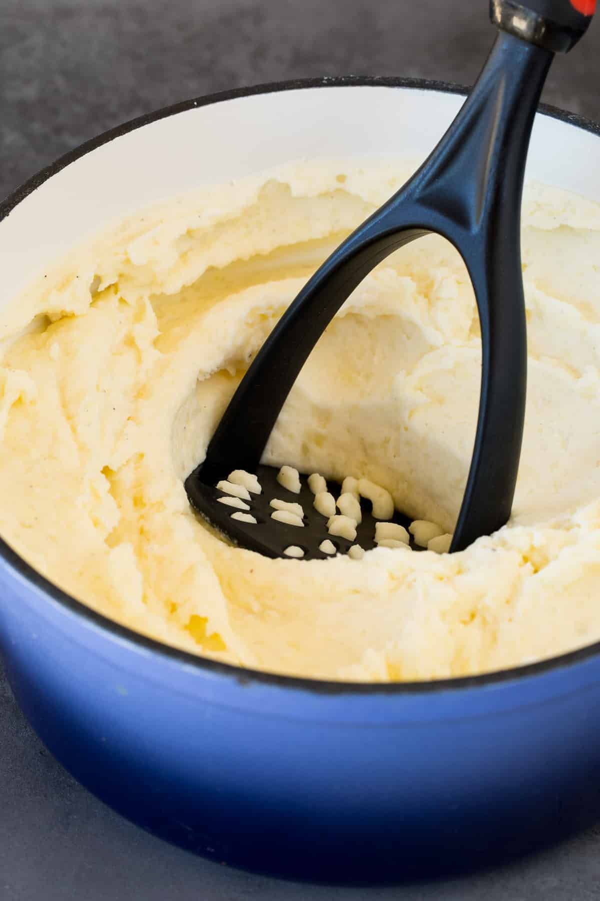 A potato masher in a pot of potatoes.