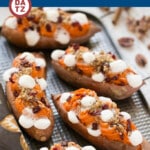 Several twice baked sweet potatoes on a sheet pan with streusel topping and marshmallows.