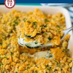 A baking dish with creamy zucchini casserole and a serving spoon with more casserole.