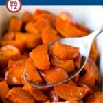 A baking dish with candied sweet potatoes and a spoon serving some sweet potatoes.