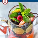 A pitcher of champagne punch with berries and lime slices.