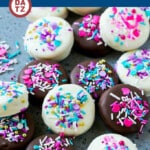 Several chocolate covered Oreos with white and dark chocolate and sprinkles.