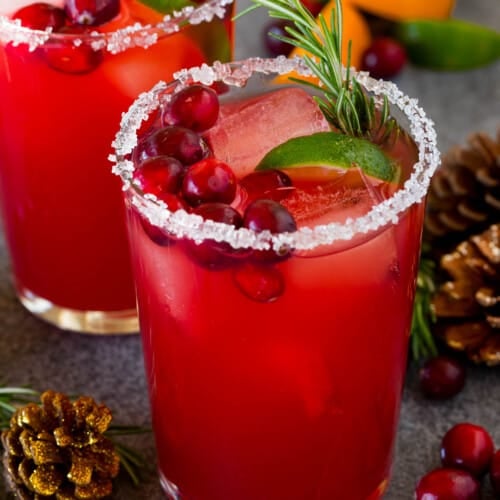 A Christmas margarita with a sugar rim on the class, and garnishes of cranberry, lime and rosemary.