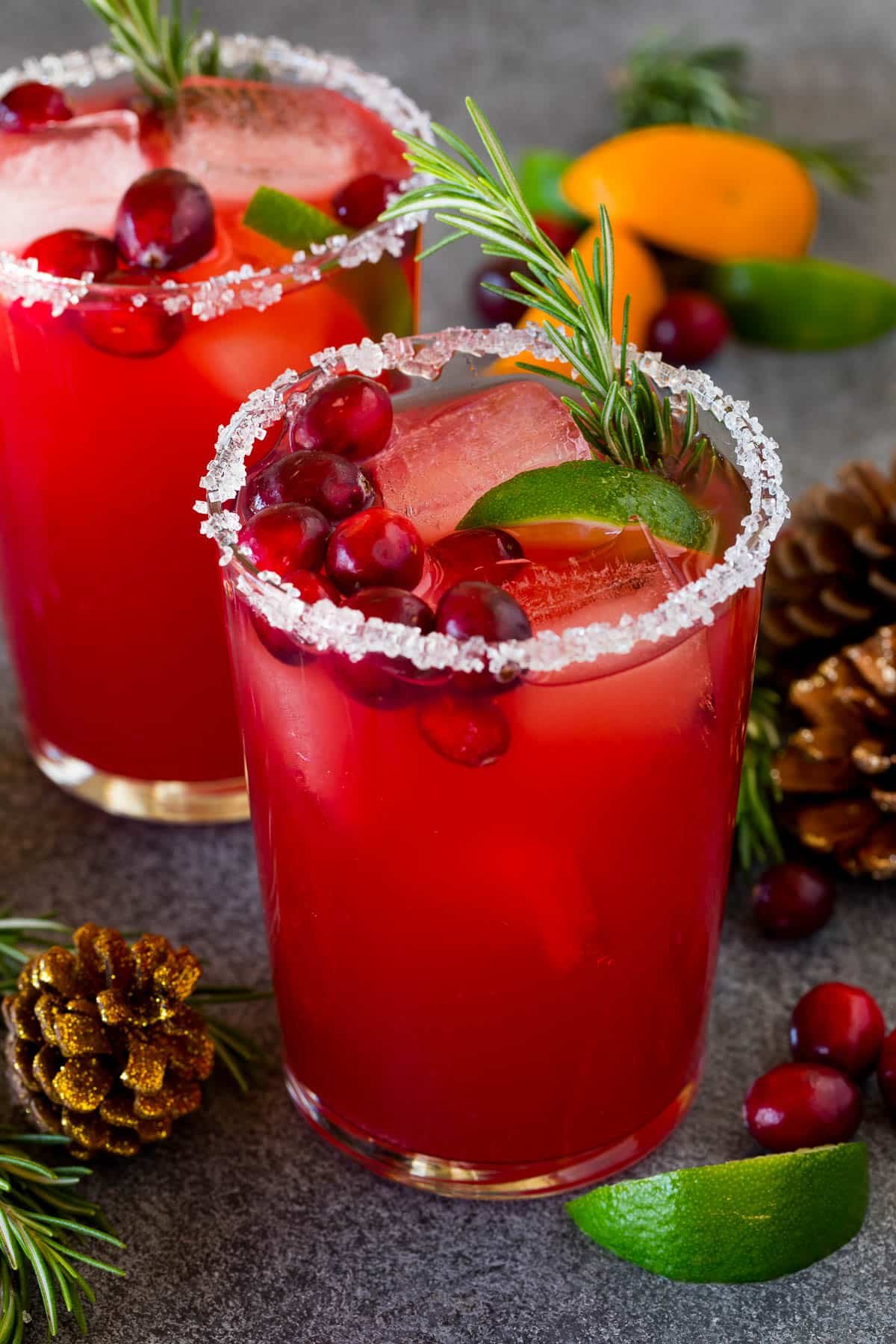 A Christmas margarita with a sugar rim on the class, and garnishes of cranberry, lime and rosemary.