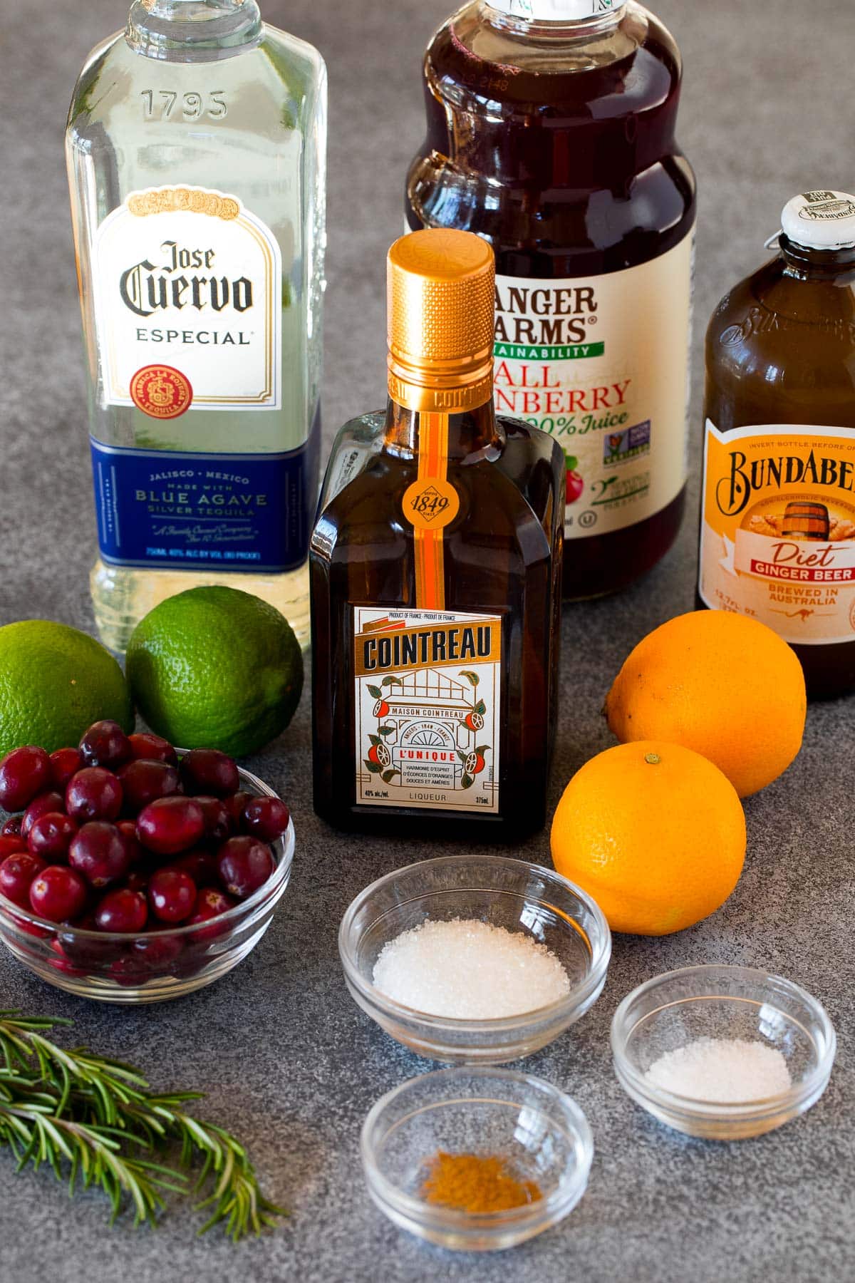 Ingredients including bottles of liquor, oranges, limes, sugar and cranberries.