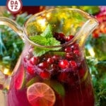 A pitcher of Christmas Punch with cranberries, lime and mint as garnishes.