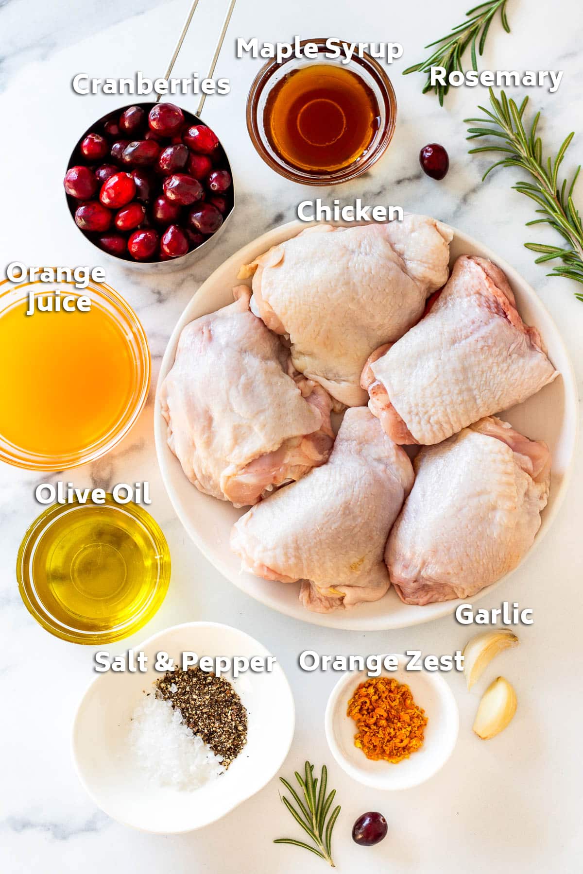 Ingredients including chicken thighs, orange juice, cranberries, maple syrup, garlic and rosemary.