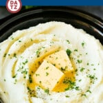 Crock pot mashed potatoes with pats of butter and chopped parsley on top.