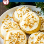 A plate of eggnog cookies with frosting and white and gold sprinkles.