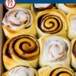 Several homemade cinnamon rolls in a baking pan with frosting.