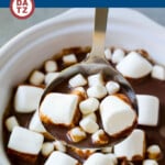 A crock pot full of slow cooker hot chocolate with marshmallows being ladled.