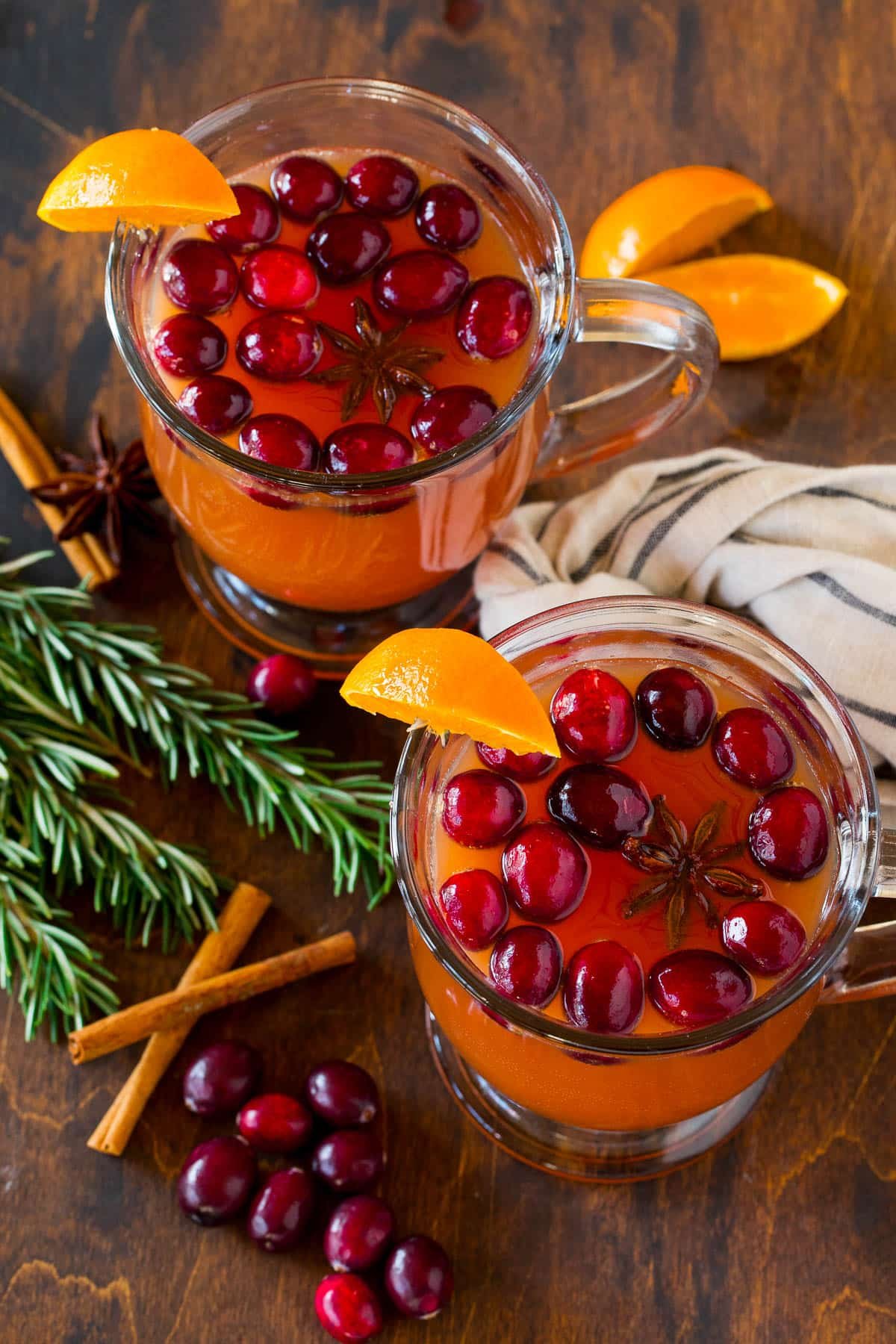 Two glasses filled with fall punch, garnished with fruit and spices.