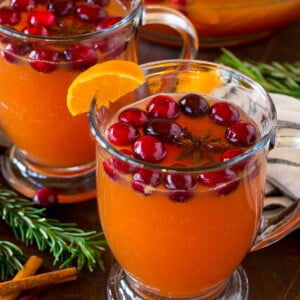 Mugs of thanksgiving punch garnished with cranberries and oranges.
