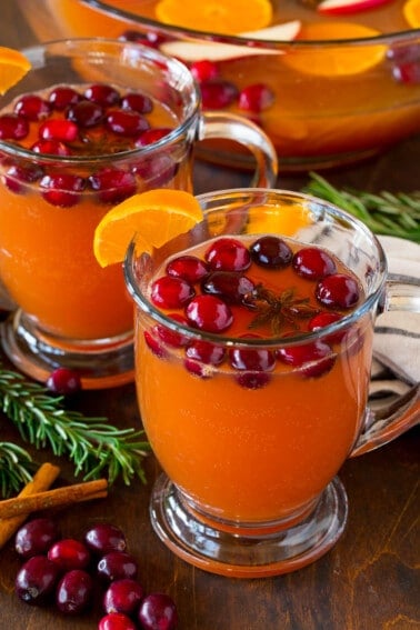 Mugs of thanksgiving punch garnished with cranberries and oranges.