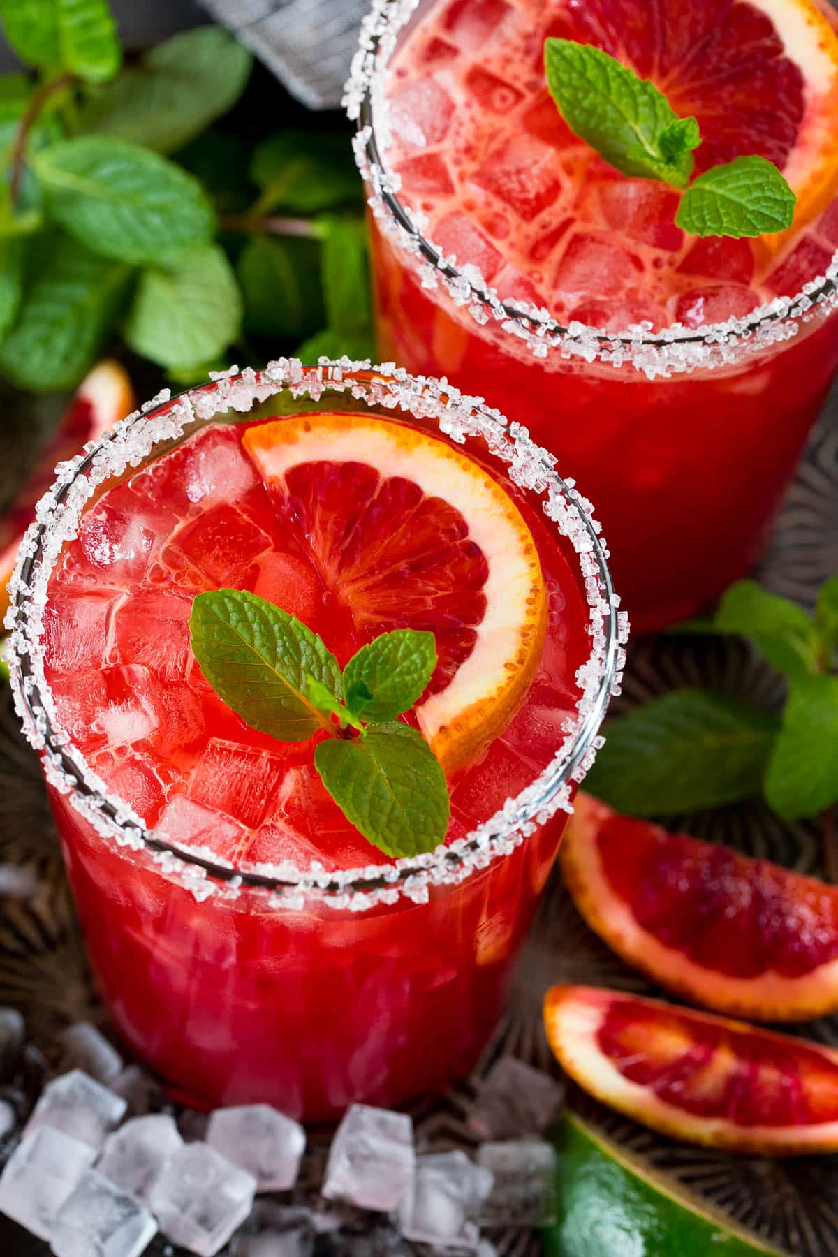 An overhead view of a blood orange margarita with garnishes of orange slices and mint.