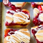 A baking sheet with cherry bars drizzled with vanilla glaze.