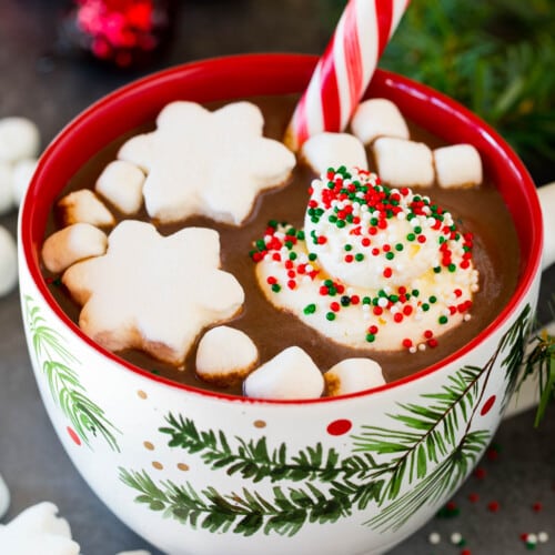 A mug of Christmas hot chocolate topped with sprinkles, whipped cream and marshmallows.