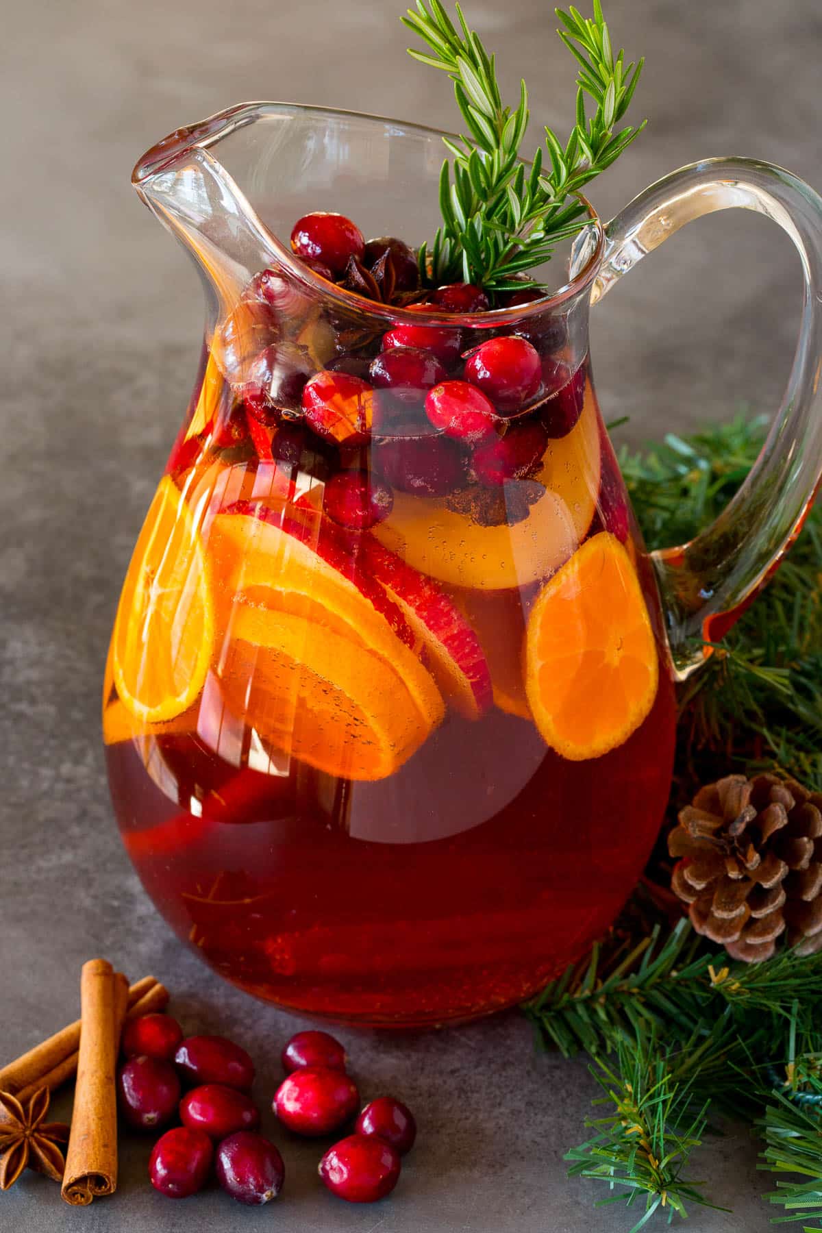 A pitcher of Christmas sangria filled with sliced fruit and cranberries.