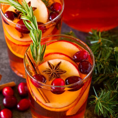 Glasses of Christmas sangria garnished with fresh fruit, cinnamon and rosemary.