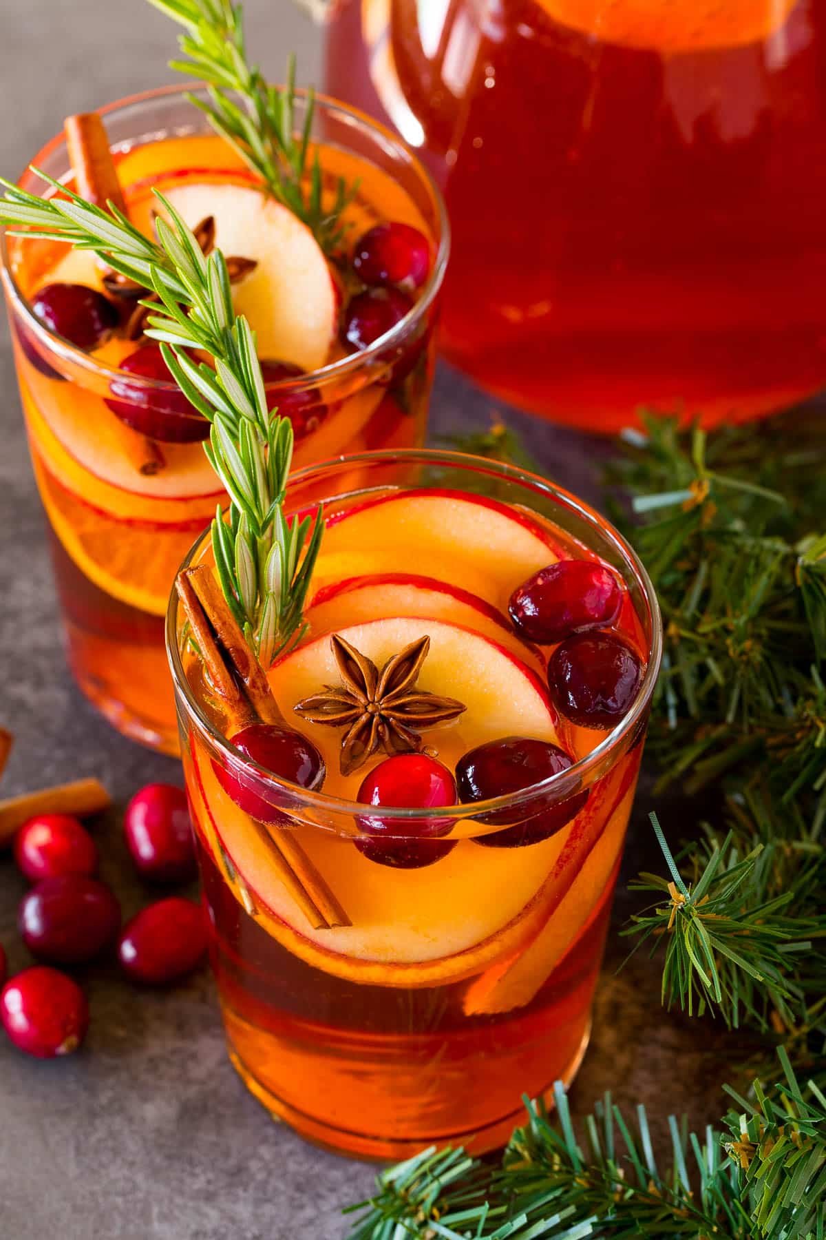 Glasses of Christmas sangria garnished with fresh fruit, cinnamon and rosemary.