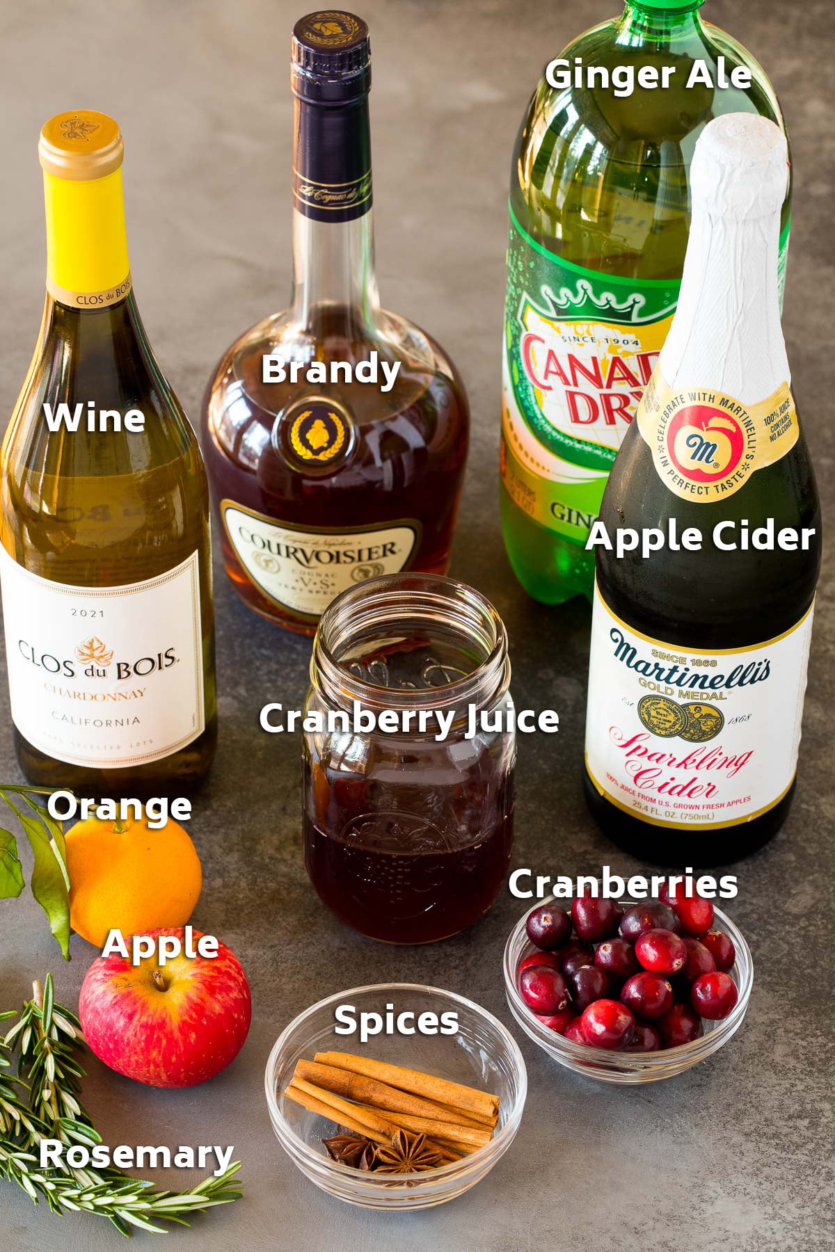 Ingredients including bottles of brandy, wine, apple cider, ginger ale and also fruit and spices.