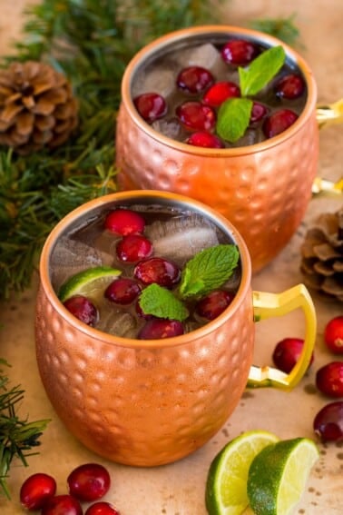 Mugs of cranberry moscow mule topped with fresh cranberries.