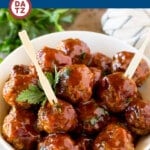 A bowl of grape jelly meatballs with appetizer forks.