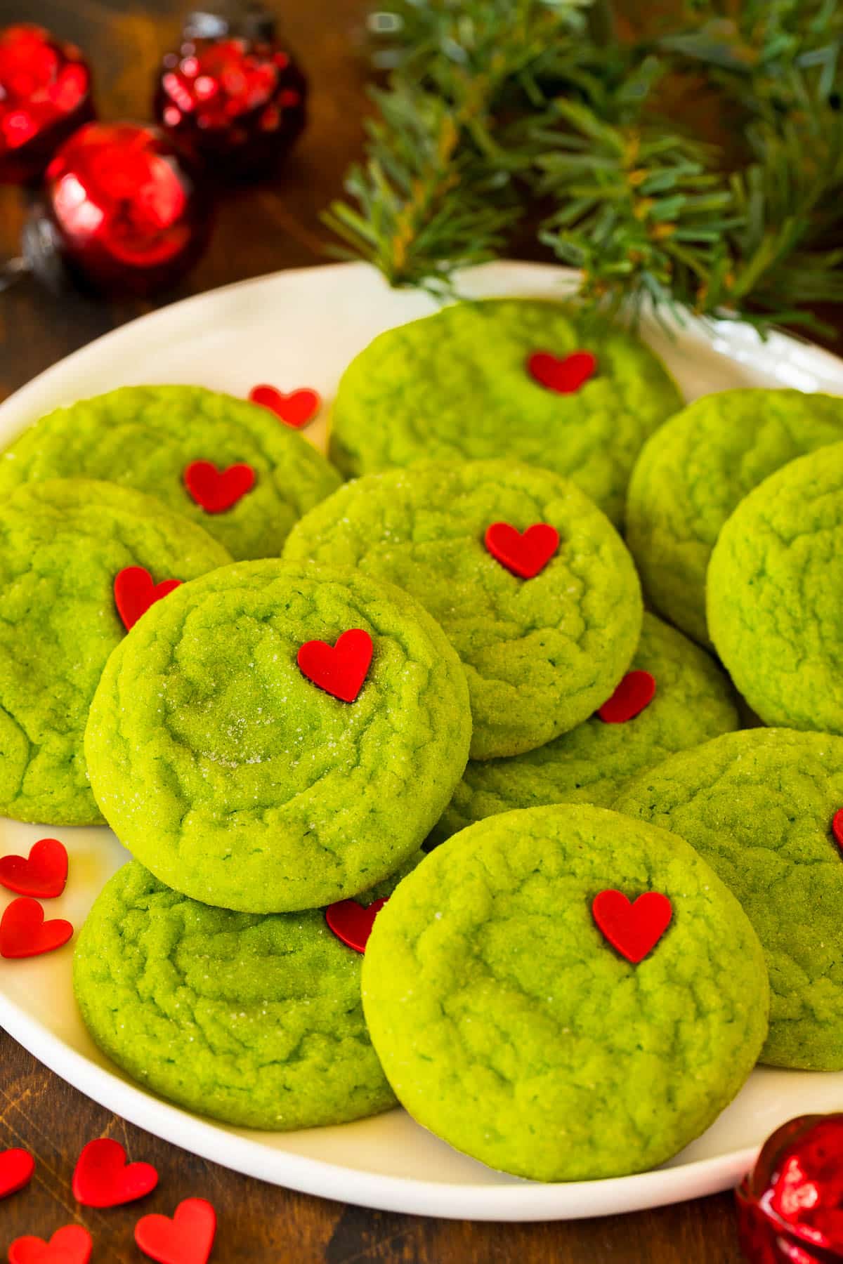 A plate of Grinch cookies with heart sprinkles on top of them.