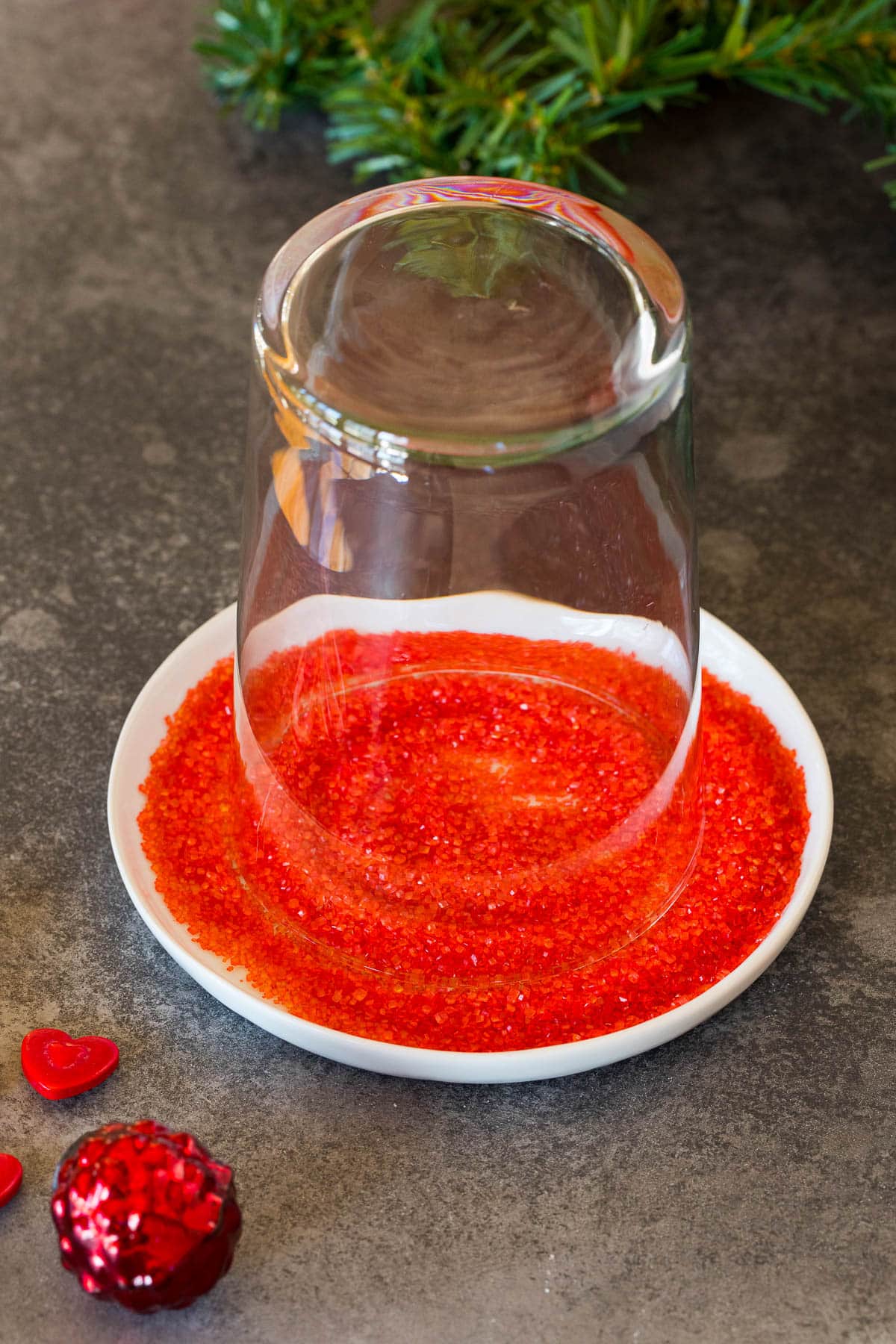 A glass on a plate of red sanding sugar.