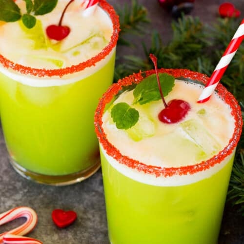 Cups of Grinch punch topped with cherries and mint sprigs.