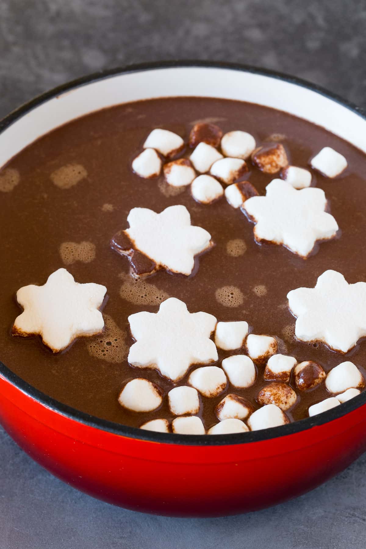 A pot of peppermint hot cocoa with marshmallows floating in it.
