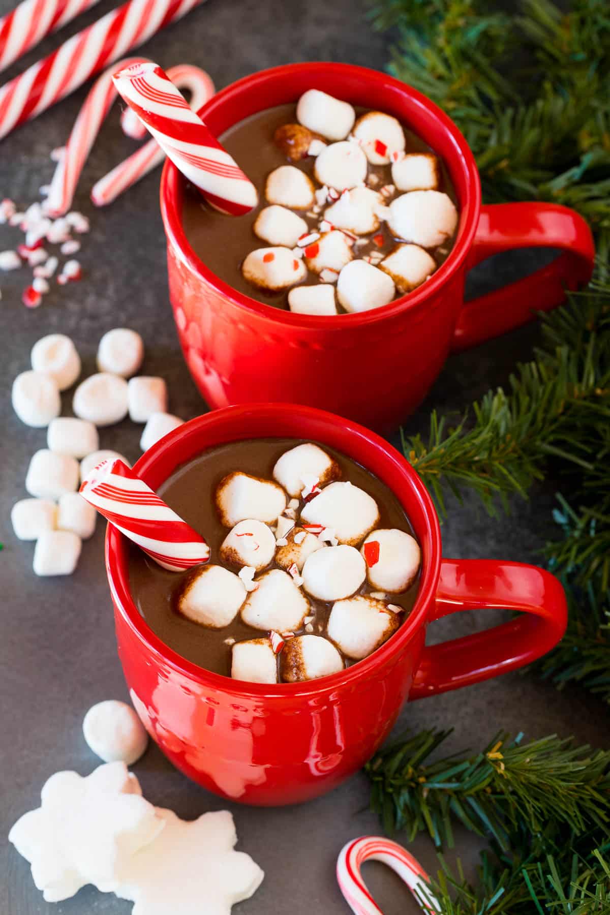 Two red mugs full of peppermint hot chocolate topped with marshmallows.