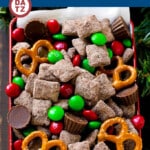 A tin of reindeer chow with chocolate coated cereal, candy and pretzels.