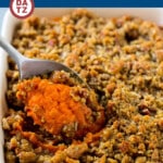 A dish of copycat Ruth's Chris sweet potato casserole being served with a spoon.