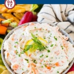 A bowl of smoked salmon dip surrounded by celery, veggies and toasted crostini.
