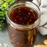A jar of homemade stir fry sauce surrounded by fresh vegetables.