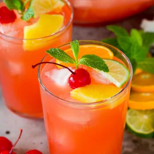 Cups of vodka punch topped with fruit and fresh mint.