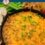 A skillet of buffalo ranch chicken dip served with carrots, bread, chips and celery.