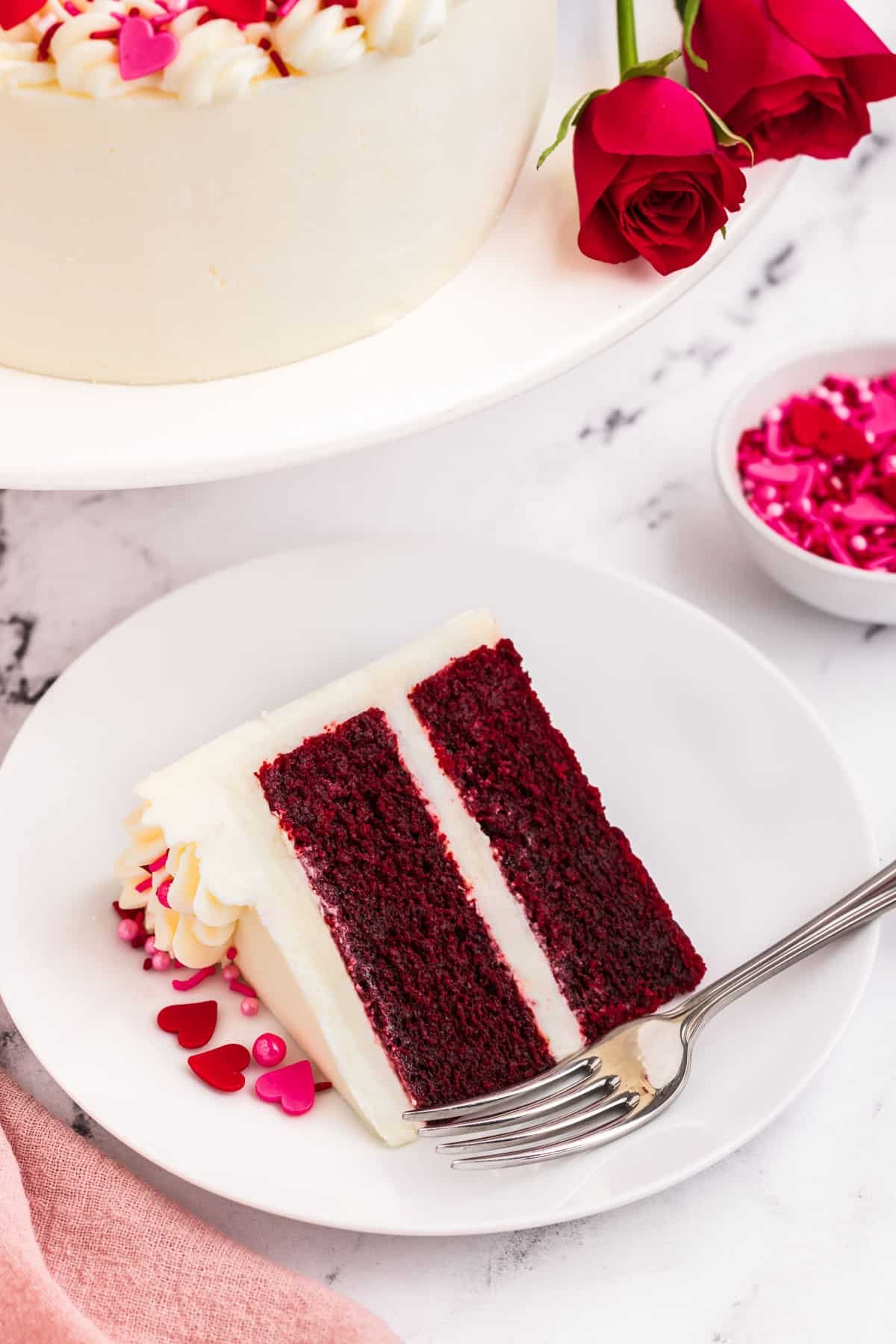 A slice of red velvet heart cake with a fork on the plate.