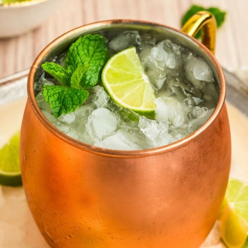 An Irish mule drink in a copper mug topped with a lime and mint sprig.
