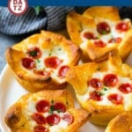 A plate of pizza muffins with sauce, cheese and mini pepperoni.