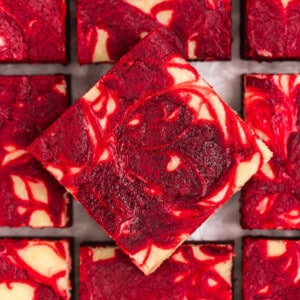 Red velvet brownies with a cheesecake swirl on a sheet of parchment paper.