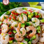 Shrimp ceviche in a bowl with avocado, onion, tomato and cucumber in a citrus marinade.
