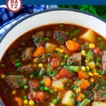A pot of vegetable beef soup with meat, veggies and potatoes in a savory broth.