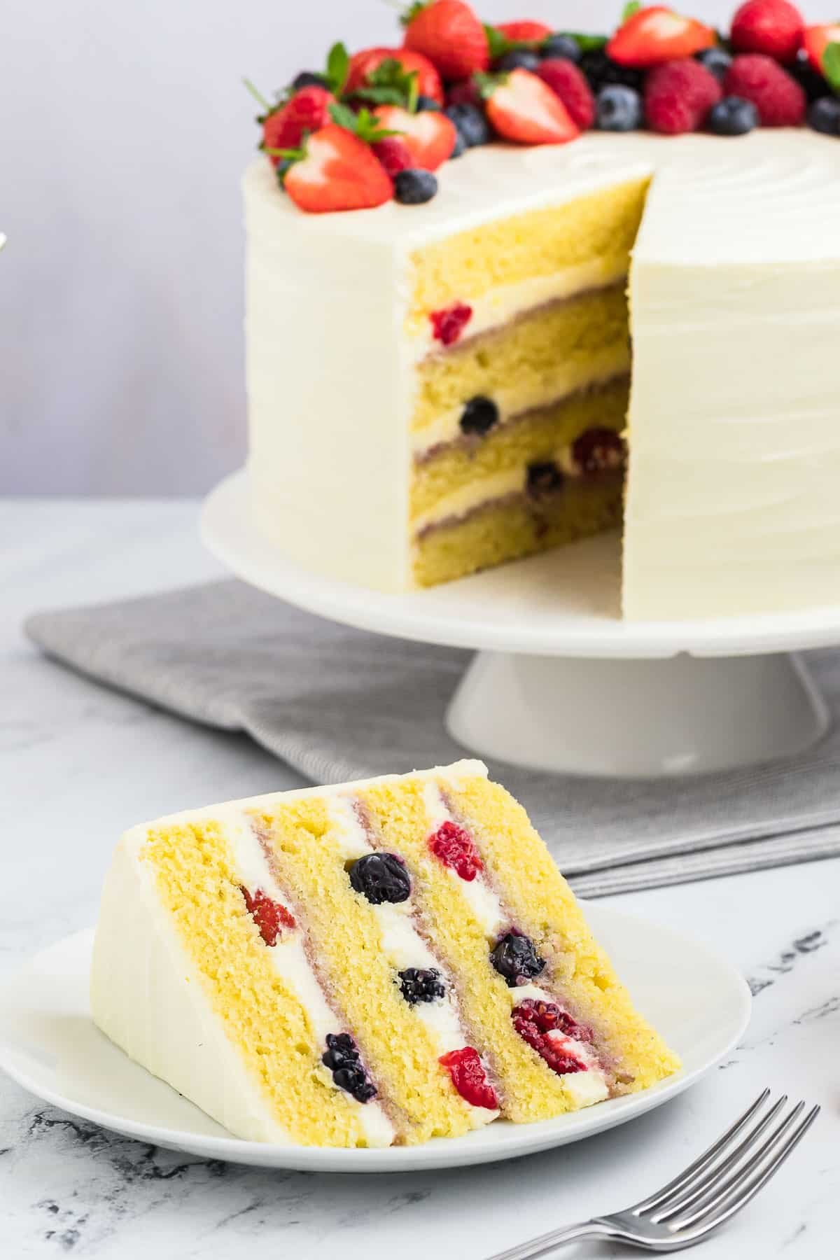 A chantilly cake with a slice cut out of it on a plate.