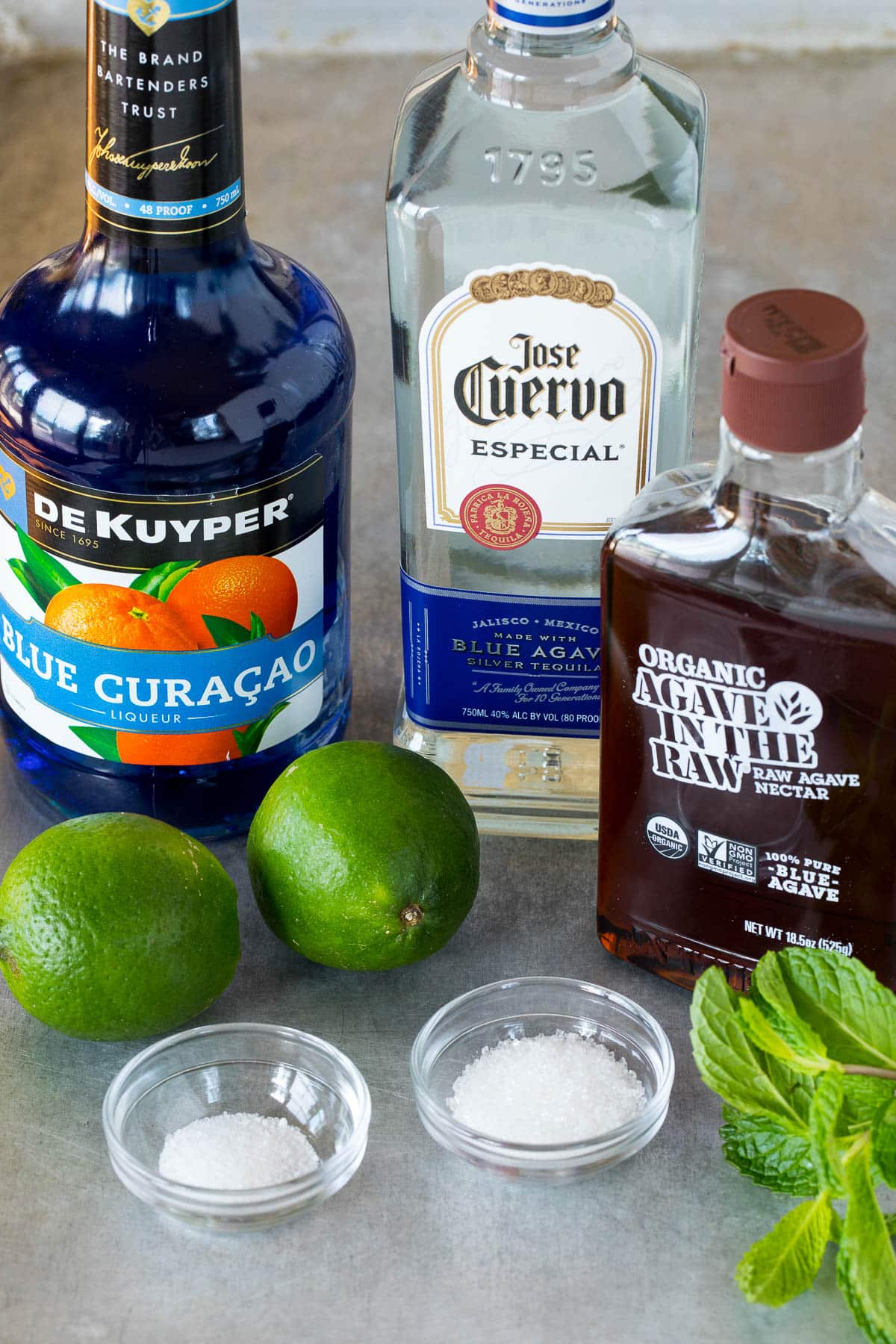 Ingredients including bottles of liquor, limes, mint and sugar.