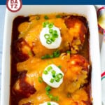 A baking dish with salsa chicken topped with salsa, cheddar cheese, sour cream and green onions.